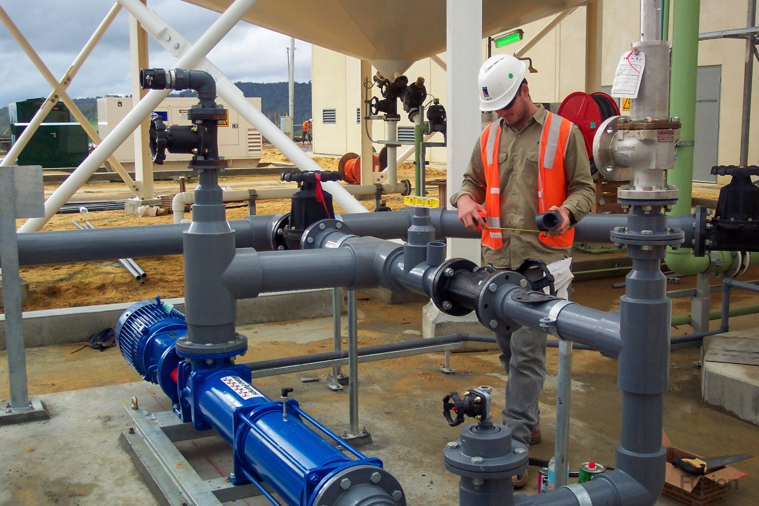 Image of a Fusion employee inspecting UPVC pipe work at an industrial site in Australia
